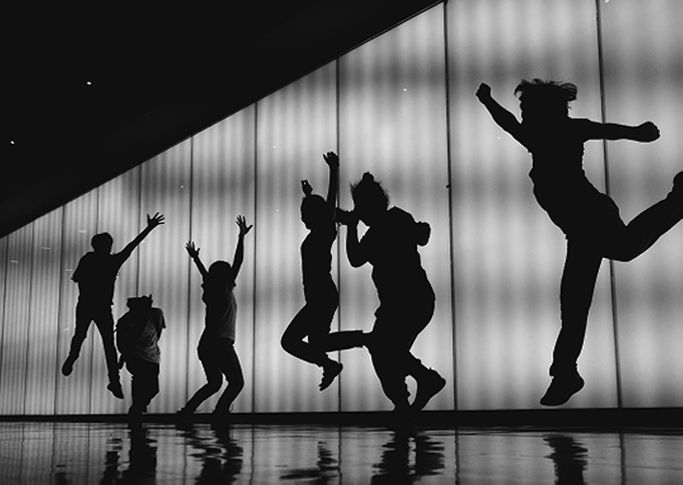 Black and white silhouettes of dancers jumping on stage