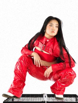 Dancer squatting in red latex pants and cropped jacket