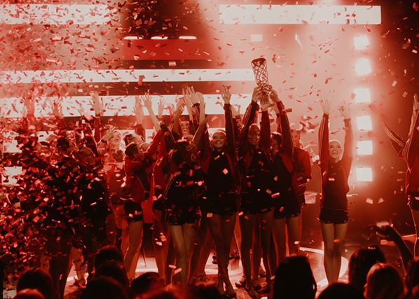 Group of dancer celebrating on stage with trophy while confetti falls
